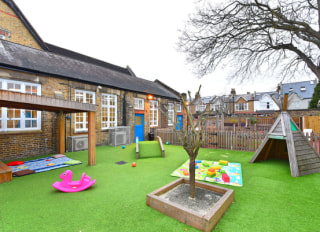 Home from home nursery exterior playground with astroturf and climbing apparatus.