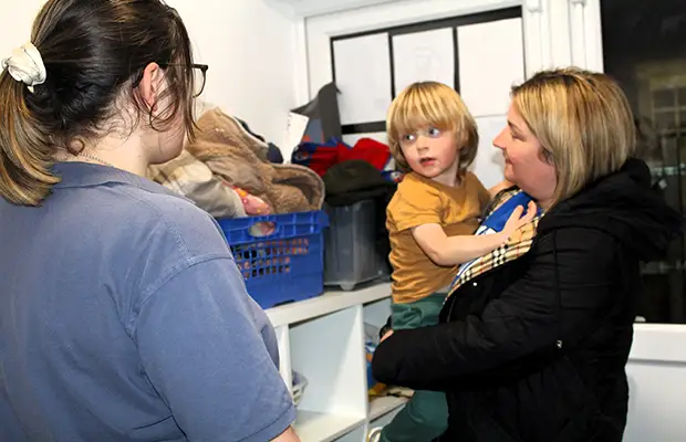 A home from home nursery worker saying goodbye to a mother and child.